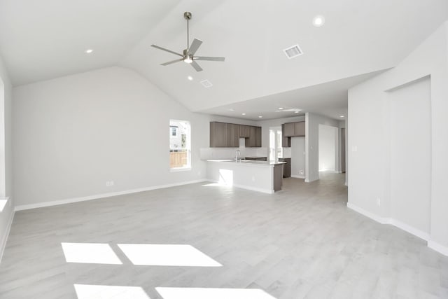 unfurnished living room with light wood-type flooring, high vaulted ceiling, ceiling fan, and sink