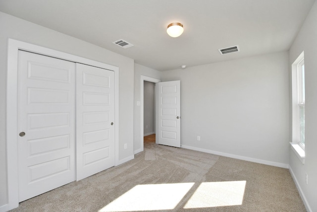 unfurnished bedroom featuring light colored carpet, multiple windows, and a closet