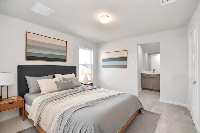 bedroom featuring ensuite bathroom and light carpet