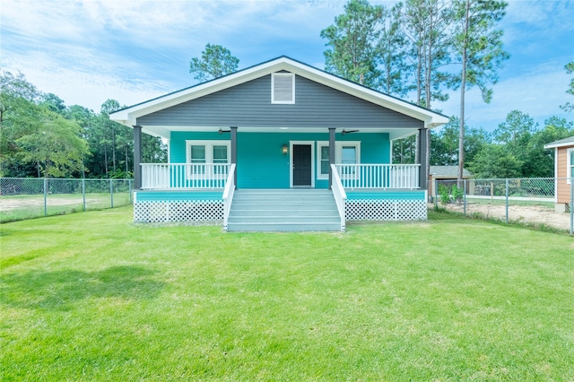 view of front of house with ceiling fan, a front yard, and covered porch