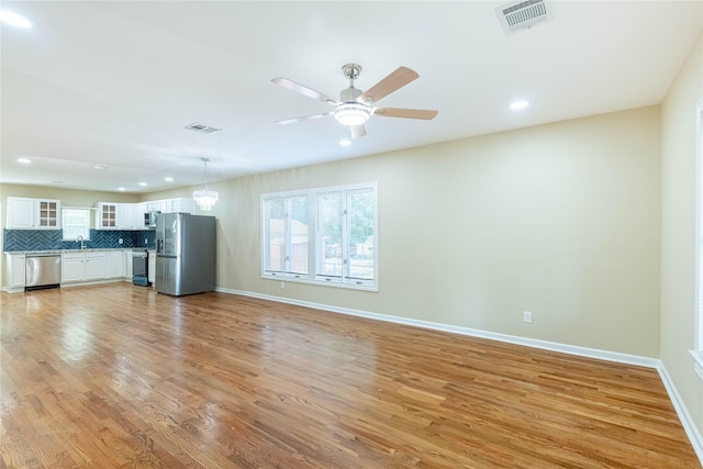 unfurnished living room featuring light wood-type flooring, plenty of natural light, visible vents, and a sink