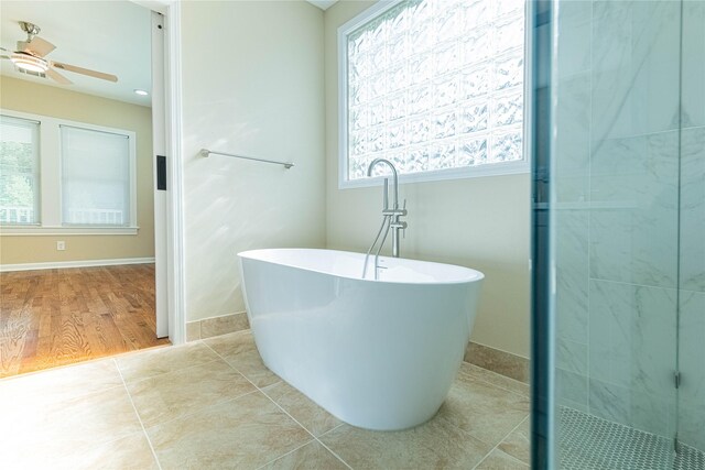 bathroom with ceiling fan, separate shower and tub, and wood-type flooring