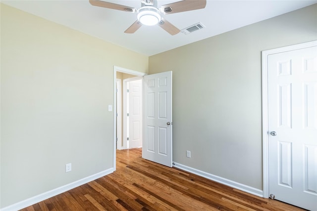 unfurnished bedroom featuring a ceiling fan, visible vents, baseboards, and wood finished floors