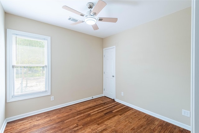 spare room featuring dark wood-style floors, ceiling fan, visible vents, and baseboards