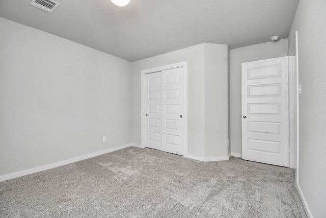 unfurnished bedroom with a closet and light colored carpet