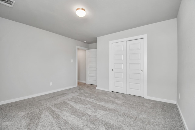 unfurnished bedroom featuring light colored carpet and a closet