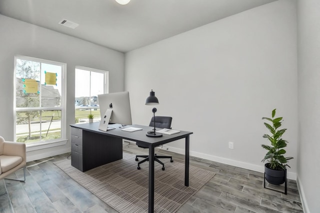 office with light hardwood / wood-style flooring and a healthy amount of sunlight