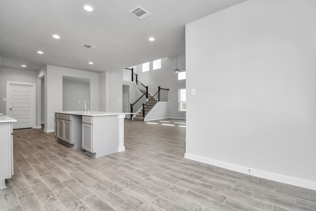 kitchen featuring a kitchen island with sink, sink, and light wood-type flooring