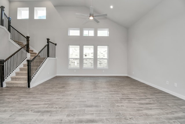 unfurnished living room with light hardwood / wood-style flooring, a healthy amount of sunlight, high vaulted ceiling, and ceiling fan