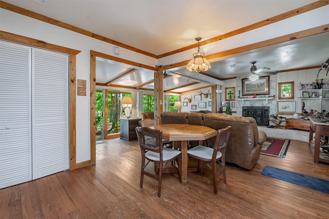 dining area with ceiling fan, a fireplace, lofted ceiling with beams, and wood-type flooring