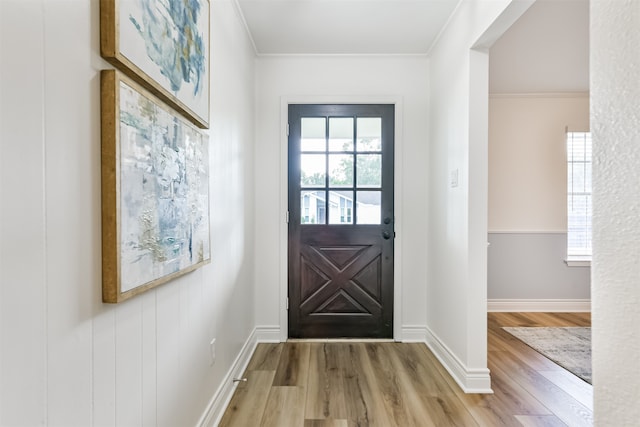 doorway with light hardwood / wood-style floors and crown molding