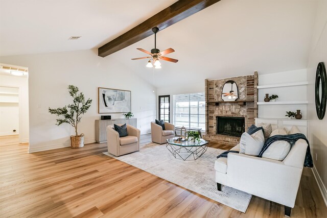 living room with a fireplace, light wood-type flooring, beamed ceiling, and ceiling fan