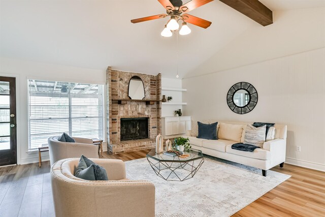 living room with ceiling fan, a fireplace, light hardwood / wood-style flooring, and beam ceiling