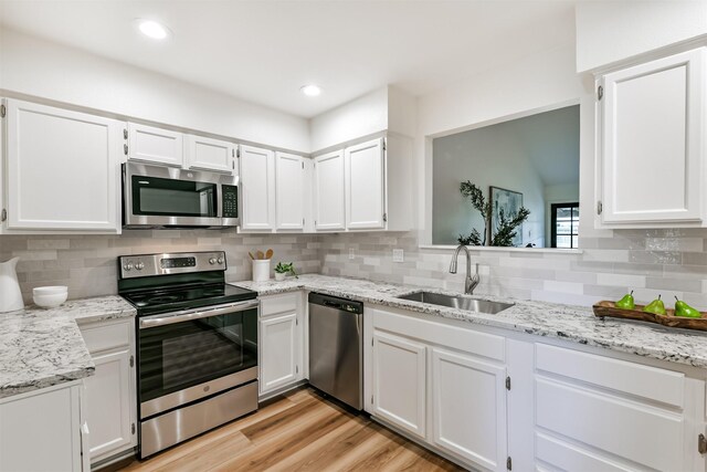 kitchen with sink, stainless steel appliances, tasteful backsplash, and light hardwood / wood-style flooring