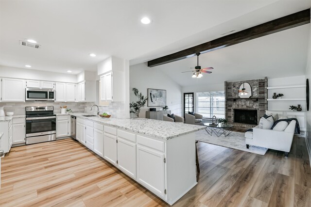 kitchen featuring vaulted ceiling with beams, light wood-type flooring, light stone countertops, and stainless steel appliances