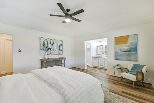 bedroom with light hardwood / wood-style flooring, ceiling fan, and ensuite bath