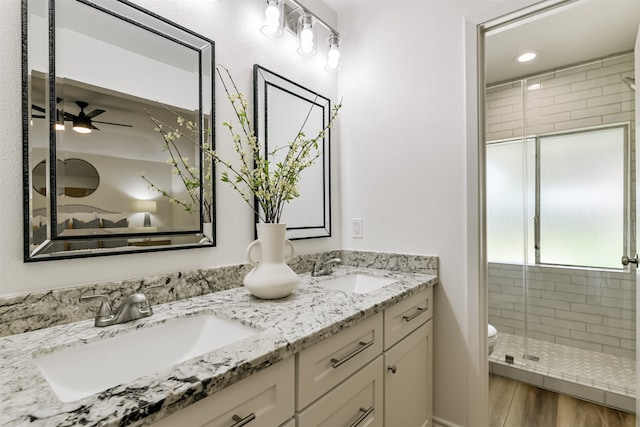 bathroom featuring vanity, a shower with shower door, ceiling fan, toilet, and hardwood / wood-style flooring