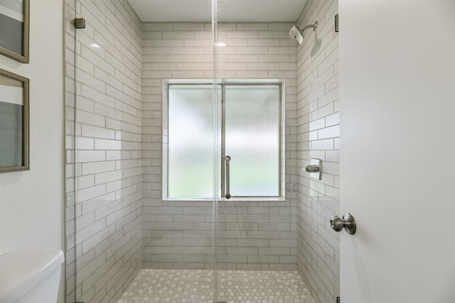 bathroom featuring toilet and a shower with shower door