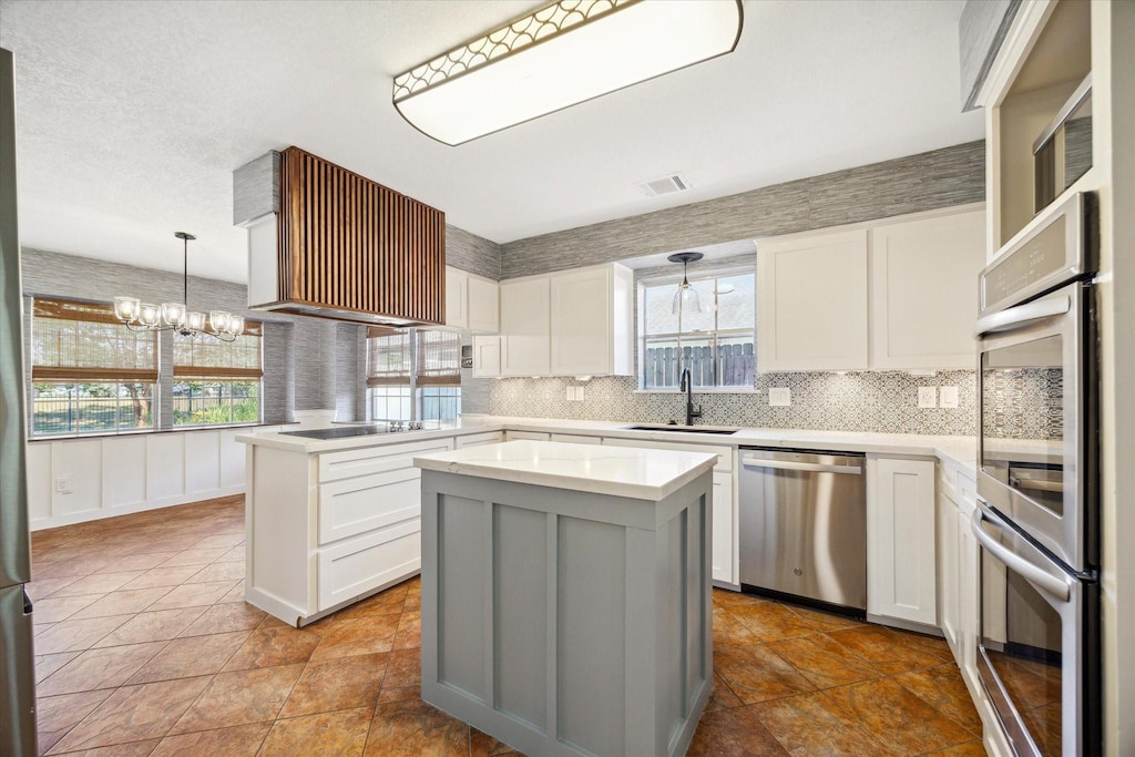 kitchen featuring white cabinets, a kitchen island, sink, and appliances with stainless steel finishes