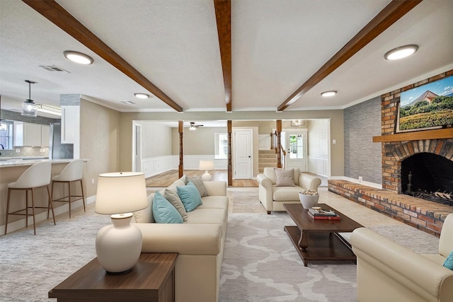 carpeted living room with beamed ceiling, ceiling fan, and a fireplace