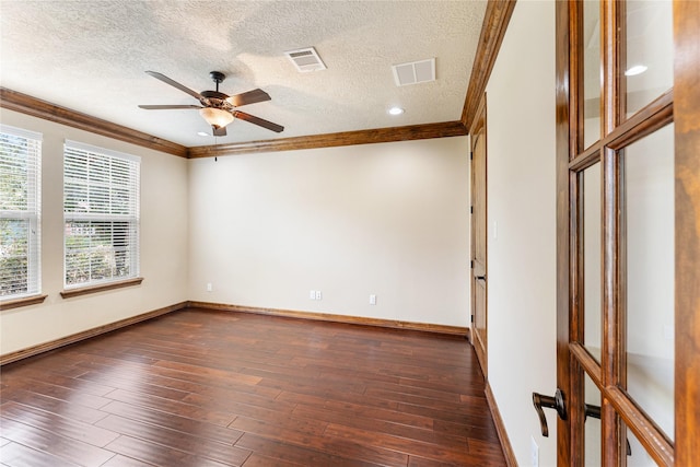 empty room with dark wood-style floors, visible vents, and crown molding