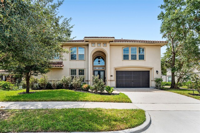 mediterranean / spanish-style home with a garage and a front lawn