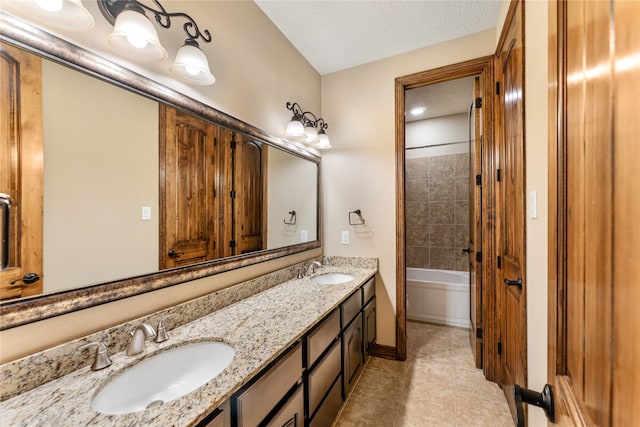 full bath with double vanity, a textured ceiling, a sink, and tile patterned floors