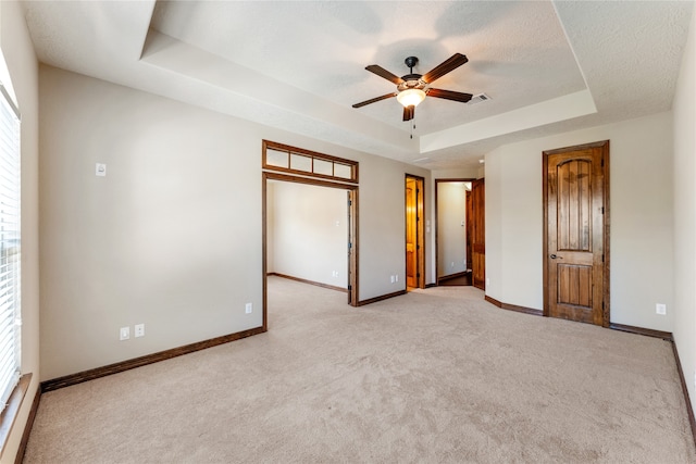 unfurnished bedroom with a tray ceiling, multiple windows, and baseboards