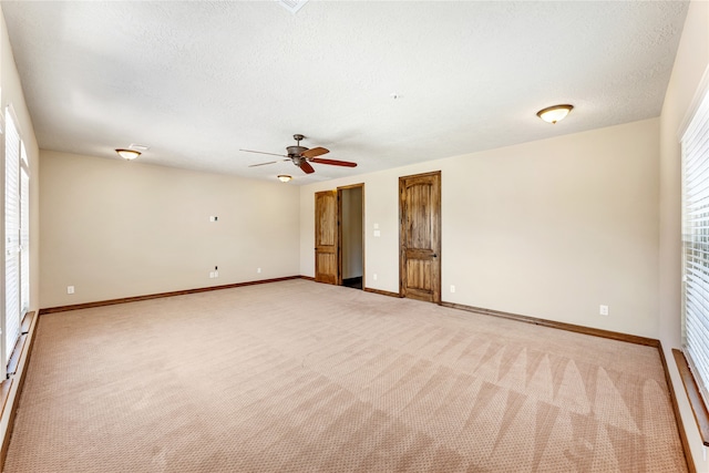 unfurnished room featuring a textured ceiling, ceiling fan, light colored carpet, and baseboards