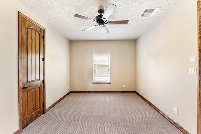 unfurnished room featuring light colored carpet, visible vents, ceiling fan, a textured ceiling, and baseboards