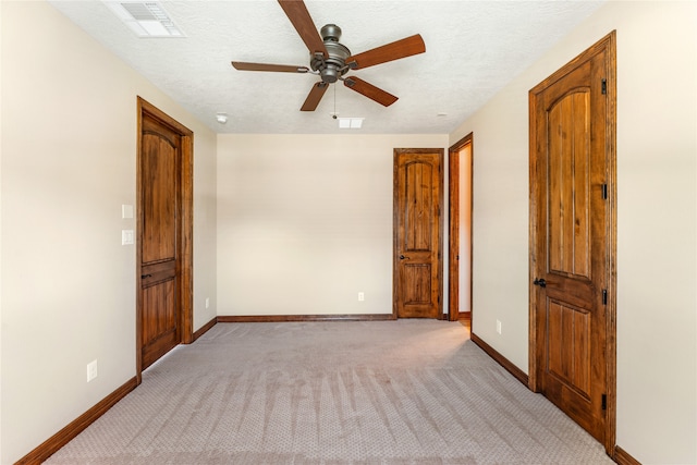 unfurnished room with visible vents, light colored carpet, a textured ceiling, and baseboards