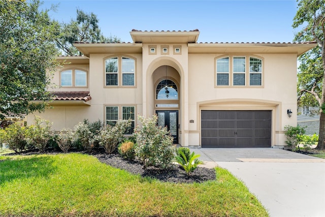 mediterranean / spanish-style home featuring an attached garage, concrete driveway, french doors, a tiled roof, and stucco siding