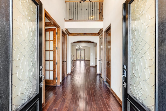 entrance foyer with baseboards, a high ceiling, arched walkways, and dark wood-style flooring