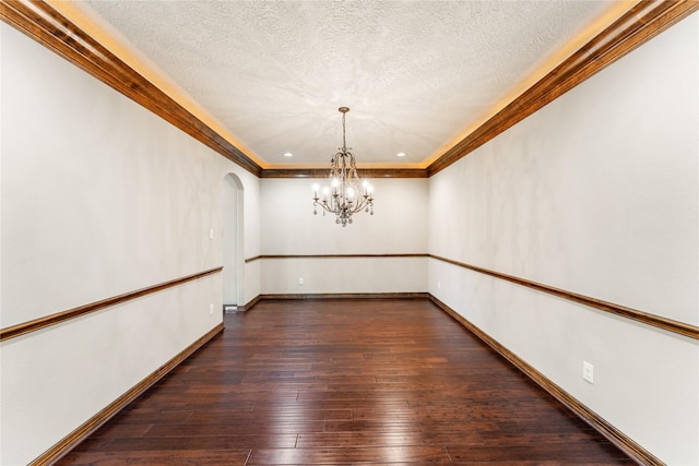 unfurnished dining area featuring baseboards, arched walkways, dark wood-style flooring, a textured ceiling, and a notable chandelier