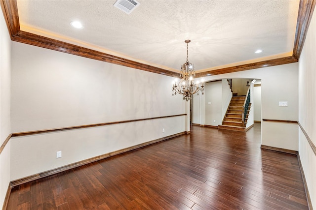 empty room featuring wood-type flooring, visible vents, and crown molding