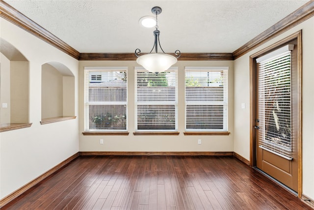 empty room featuring a textured ceiling, dark wood-style flooring, baseboards, and crown molding