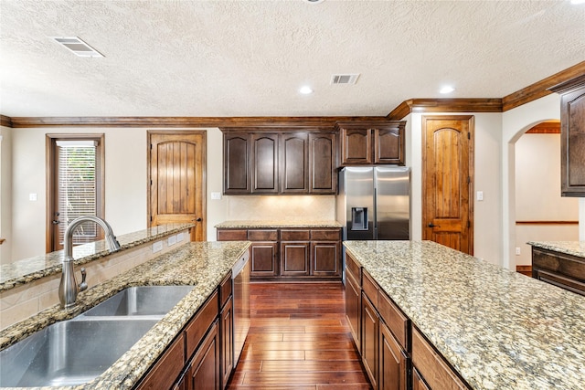 kitchen featuring stainless steel appliances, a sink, visible vents, dark wood-style floors, and tasteful backsplash