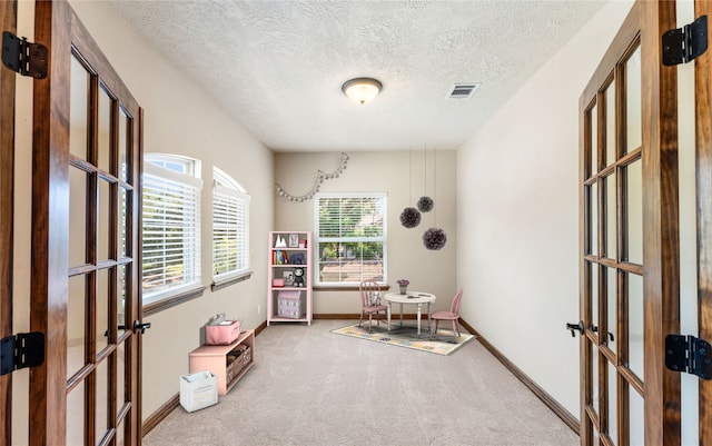 office featuring a textured ceiling, visible vents, baseboards, french doors, and carpet