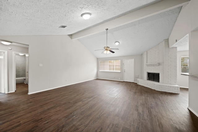 unfurnished living room featuring a brick fireplace, dark wood-type flooring, lofted ceiling with beams, ceiling fan, and brick wall