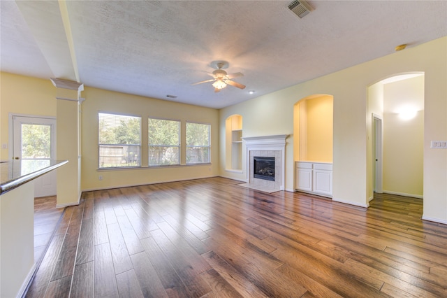 unfurnished living room with hardwood / wood-style floors, ceiling fan, a fireplace, and a textured ceiling