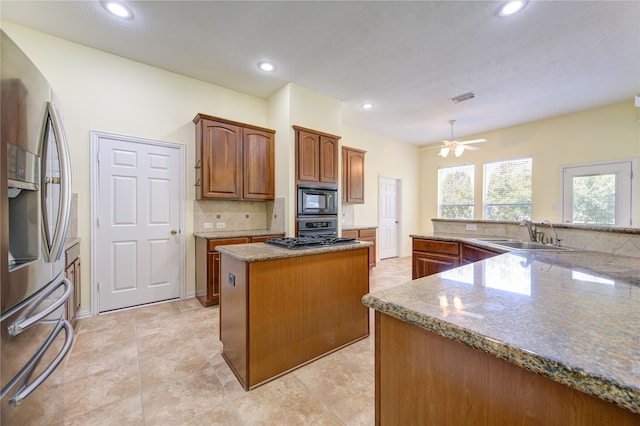 kitchen featuring a center island, stainless steel appliances, sink, ceiling fan, and tasteful backsplash