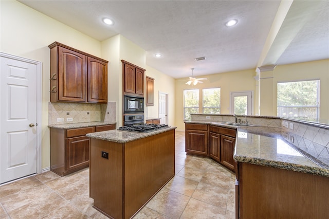 kitchen featuring appliances with stainless steel finishes, sink, ornate columns, ceiling fan, and a kitchen island