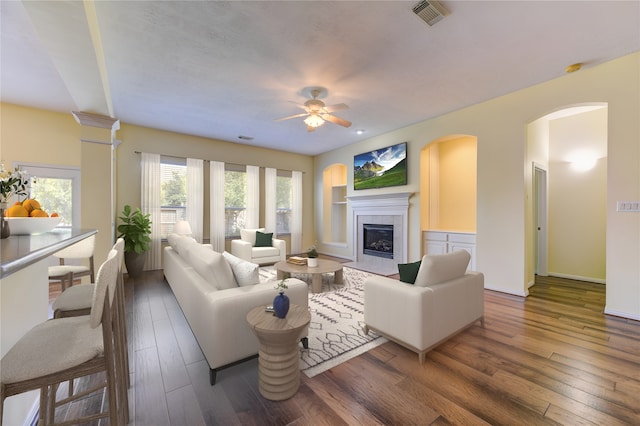 living room featuring ceiling fan, a tiled fireplace, and dark hardwood / wood-style flooring