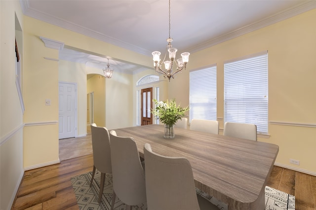 dining space with crown molding, dark hardwood / wood-style flooring, and an inviting chandelier