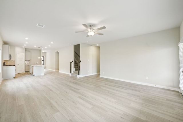 unfurnished living room with ceiling fan, sink, and light hardwood / wood-style flooring