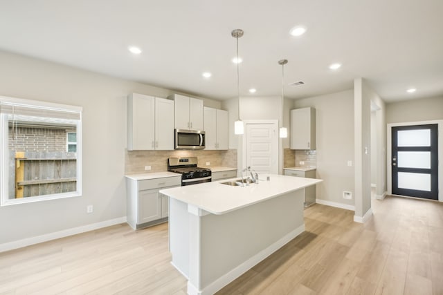 kitchen featuring pendant lighting, stainless steel appliances, sink, and light hardwood / wood-style flooring