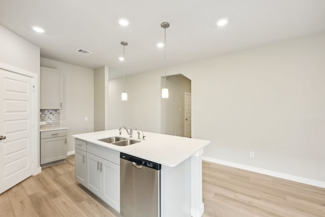 kitchen featuring sink, stainless steel dishwasher, decorative light fixtures, and a center island with sink