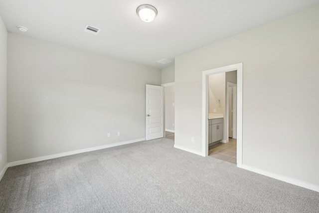 unfurnished bedroom featuring light carpet and connected bathroom