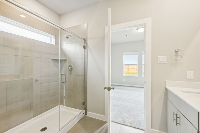 bathroom with walk in shower, vanity, and tile patterned floors