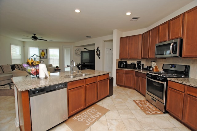 kitchen featuring backsplash, appliances with stainless steel finishes, sink, an island with sink, and ceiling fan